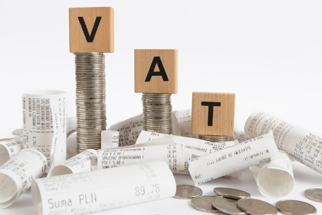 Rows of coin stacks with toy blocks among the receipts symbolizing value added tax