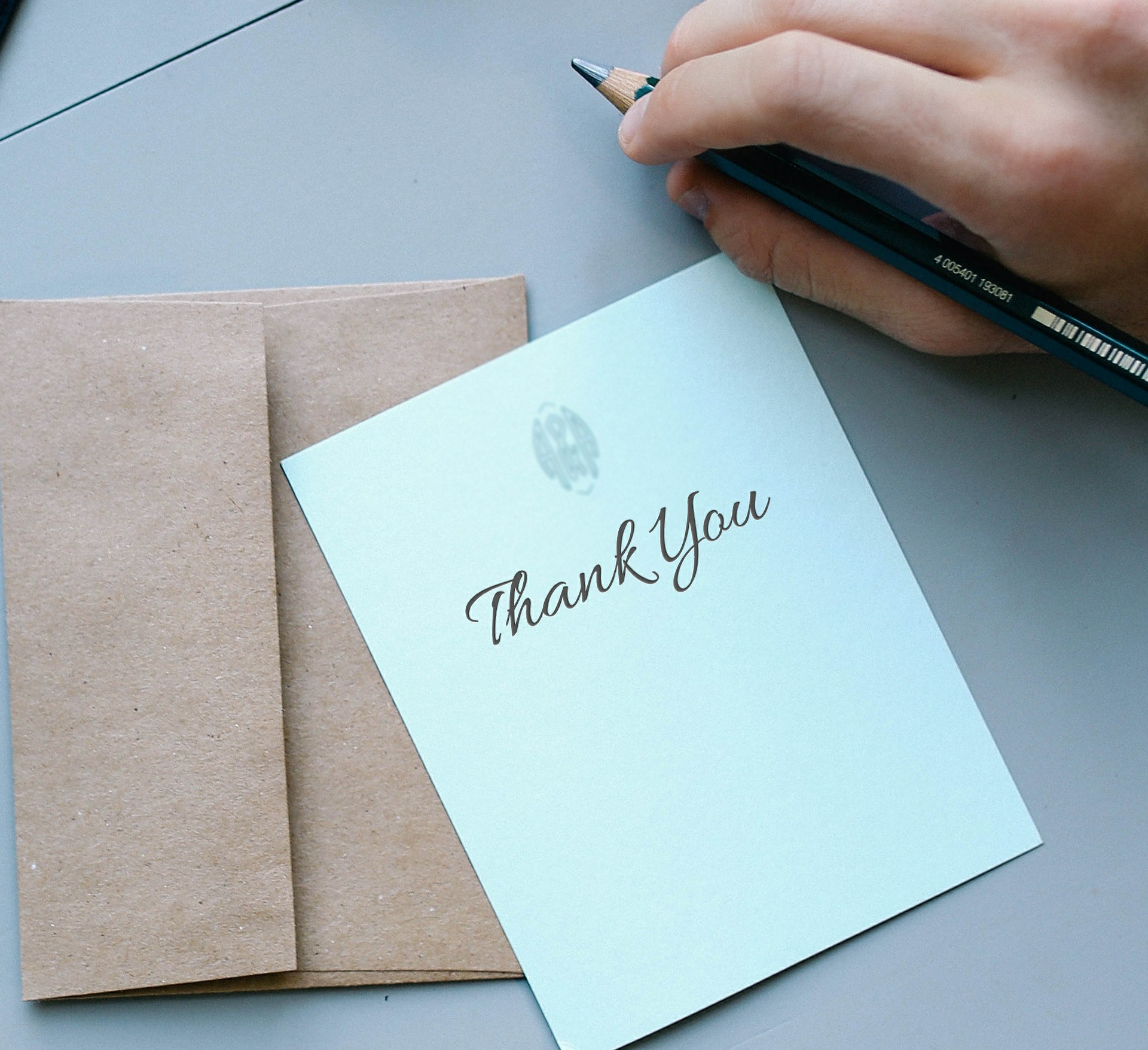 person writing a thank you card